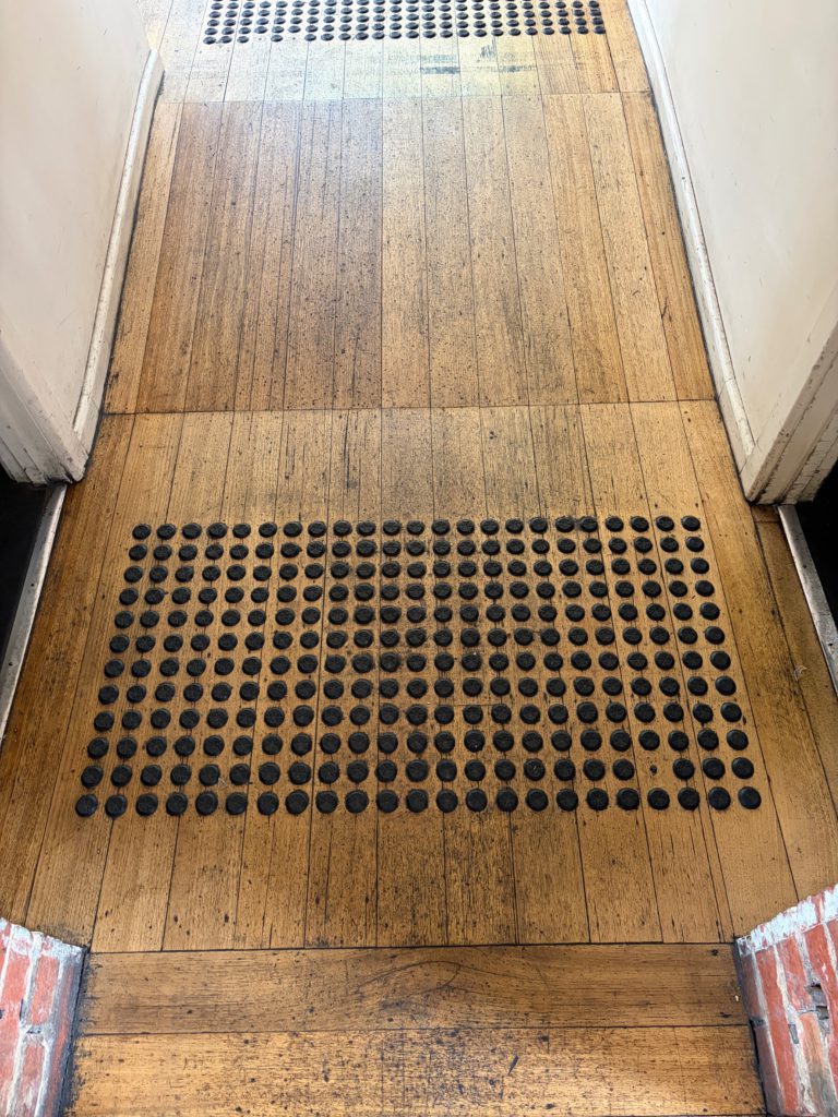 Timber-floored internal passage with raised tactile indicators.